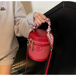 Macro shot of red leather and woven bucket bag with silk scarf handle and gold hardware