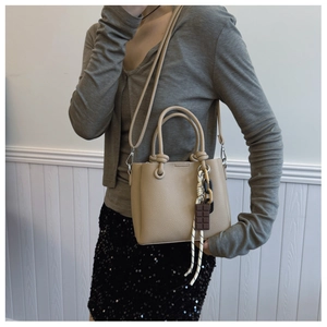 Détail du cuir grainé beige et du pendentif chocolat sur le sac seau en gros plan macro