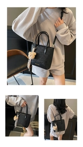 Detail of black woven bucket bag with leather handles and cute bear charm accessory