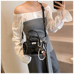 Black patent leather Boston bag with pearl bear charm shown in a mirror selfie style
