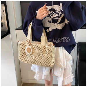 Détail du sac en paille beige tissé à la main avec crochet à mailles larges et breloque marguerite
