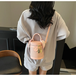Pink cylindrical bucket bag with woven texture and floral scarf handle detail