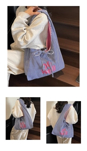 Close-up of blue striped canvas tote with pink BE WELL print and drawstring detail