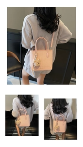 Close-up of pink woven texture bucket bag with gold logo and plush bear charm