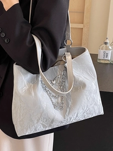 Silver wrinkled tote bag with butterfly chain on shoulder, ideal for stylish commuting