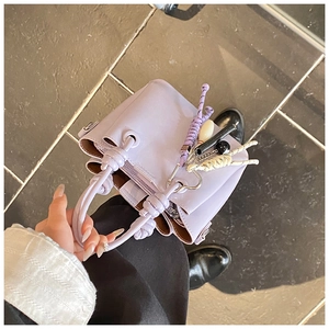 Vue de dessus d'un sac seau en cuir lilas avec fermeture éclair et pendentif décoratif
