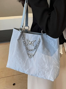Light blue tote bag with wave texture and butterfly chain shown on shoulder