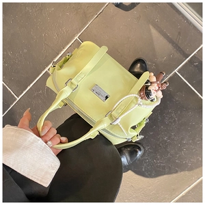 Detail view of a cream green Boston handbag featuring a pearl chain and cute doll charm