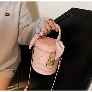 Pink bucket bag with silk scarf handle and leather patchwork detail in close-up view