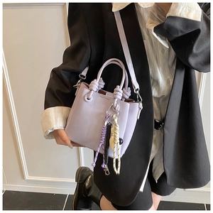 Détail du sac seau en cuir PU violet clair avec poignée à nœud tissé et breloque tricolore