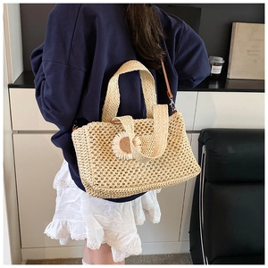 Détail du sac seau en paille tissé à la main avec charm marguerite et bandoulière en cuir