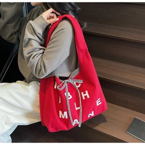 Detail of red canvas tote bag with white letters and black and white striped bow