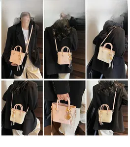 Détails d'un sac seau rose clair porté en bandoulière et à la main par un mannequin