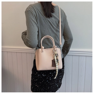 Détail du sac seau en cuir rose avec breloque chocolat et décoration de ruban élégante