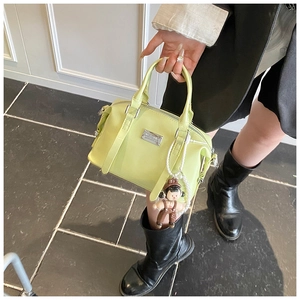 Detail of glossy olive green Boston bag with silver logo plate and pearl charm