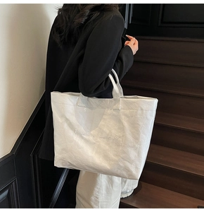 Detail of white Tyvek tote bag featuring natural crinkled texture and TOTE BAG embossing
