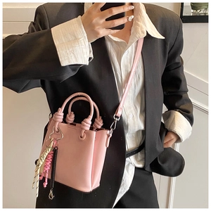 Vue détaillée du mini sac seau rose avec poignée nouée et breloques tendance
