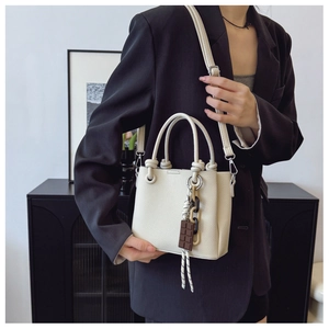 Détail du sac seau blanc cassé avec texture litchi et breloque en chocolat