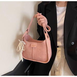 Close-up of pink lychee leather bag with pearl lace charm and fashion bags golden text