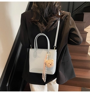 Detail of greyish blue woven texture bucket bag with cute bear charm and tassel