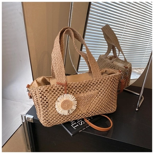 Détail d'un sac à main en paille tressée avec breloque marguerite et fine bandoulière brune