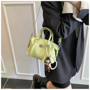 Detail of light green patent leather Boston bag with pearl charms and cartoon doll