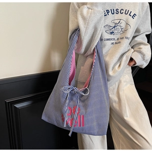 Close-up of striped canvas tote bag with pink be well print and bow tie closure