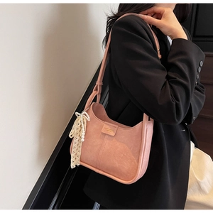 Detail view of pink suede underarm bag with pearl lace pendant on black suit