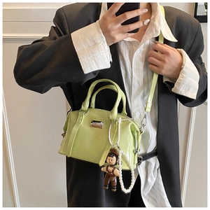 Detail of light green patent leather Boston bag with pearl and doll charm attachment