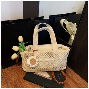 Détail du sac cabas en paille tressée avec pendentif marguerite et bandoulière en cuir brun