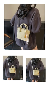 Détail du sac seau en cuir verni vert clair avec poignées et pompon décoratif