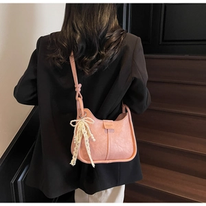 Pink hobo shoulder bag with pearl lace bow detail shown on model in black blazer