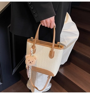 Detail of woven fabric handbag with caramel leather trim and cute plush bear charm