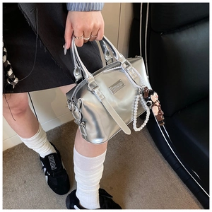 Detailed macro view of silver mirror-finish Boston bag with elegant pearl strap and doll charm