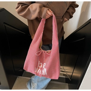 Detail of red and white striped canvas tote bag with bow tie closure and be well lettering