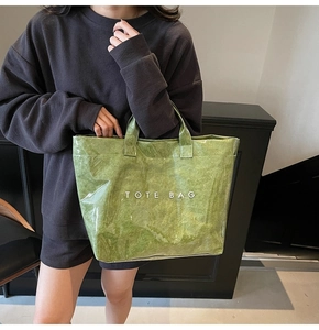 Detail shot of green tote bag with crinkle texture and white printed text on the side