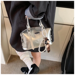Detail of silver metallic bowling bag with pearl chain and cartoon charm accessory
