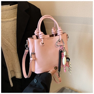 Détail du sac seau rose montrant la poignée nouée et des charms créatifs de boules