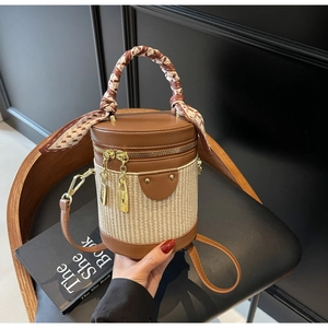 Detail of a brown leather and straw bucket bag with a silk scarf handle and metal lock