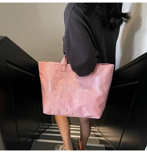 Detailaufnahme der rosa DuPont-Papier-Tote Bag mit Knitterstruktur und weißer Aufschrift