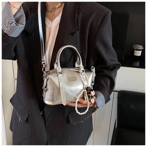 Detail view of silver Boston bag with pearl chain and cartoon toy pendant accessory