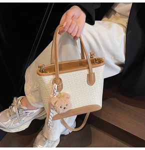 Detailed texture of woven fabric handbag with premium brown leather trim and bear charm