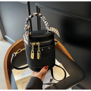 Detail of black cylinder bag with woven texture and silk scarf wrapped on handle