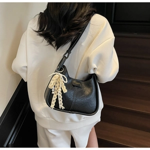 Detail showing black crescent shoulder bag with white lace pearl charm on a model