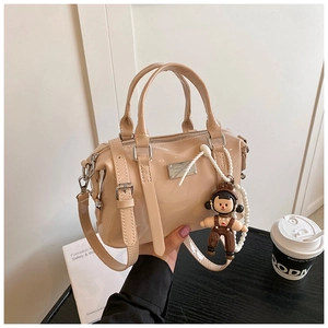Detail of glossy beige Boston bag with silver plaque and pearl bear charm