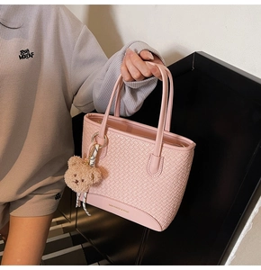 Close-up of pink woven texture bucket bag with a cute brown plush bear charm