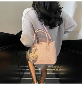 Detail of pink woven texture bucket bag with detachable strap and plush bear charm