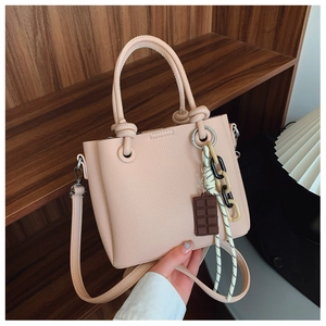 Détail du sac seau rose clair avec anses tissées et breloque en forme de chocolat