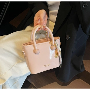 Détail du sac à main en cuir verni rose avec finition brillante et logo