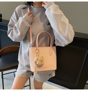 Pink woven texture bucket bag with a cute teddy bear charm and adjustable shoulder strap